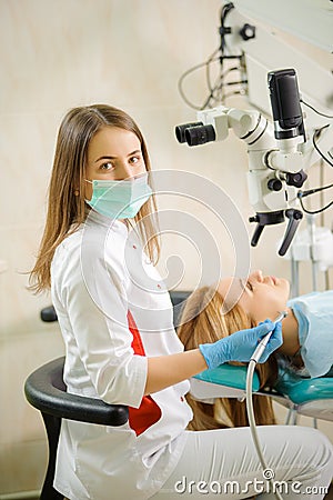 Female dentist treating caries using microscope at the dentist office Stock Photo