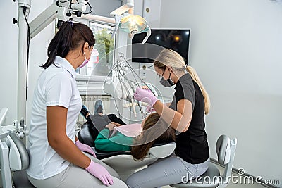 Female dentist and young assistant doing repairing patient tooth in dental ambulant Stock Photo