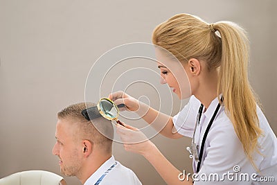 Female Dermatologist Looking Hair Through Magnifying Glass Stock Photo