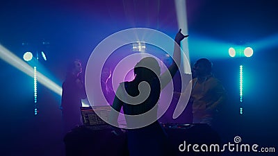 Female DJ Leading the Party at Nightclub with Crowd in Silhouette Stock Photo