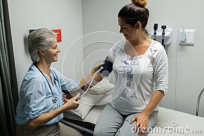 Female doctor checking blood pressure of a pregnant woman Stock Photo