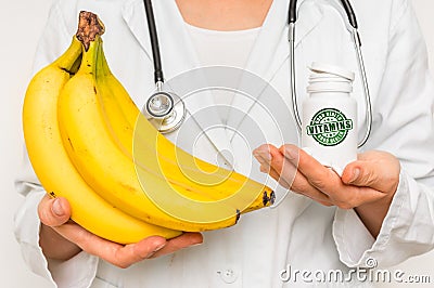 Female doctor compare pile of pills with fresh banana Stock Photo