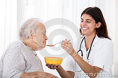 Female Doctor Feeding Soup To Senior Patient Stock Photo