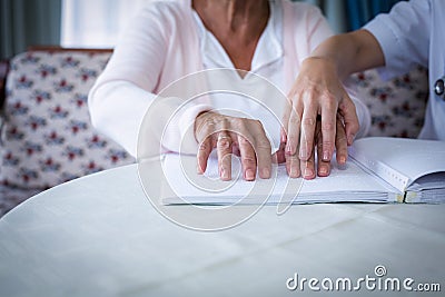 Female doctor helping a blind patient in reading the braille book Stock Photo