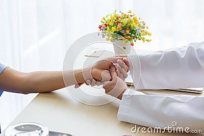 Female doctor holding patient`s hand for encouragement and empathy and touching her arm. Partnership, trust and medical Stock Photo