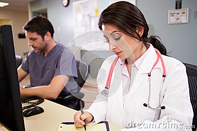 Female Doctor With Male Nurse Working At Nurses Station Stock Photo