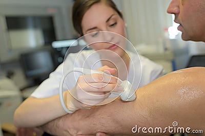 Female doctor with male patient undergoing arm echography Stock Photo