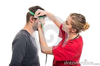Female doctor measuring male patient head Stock Photo