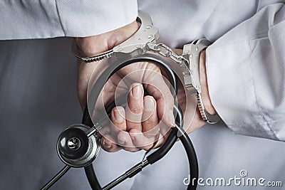 Female Doctor or Nurse In Handcuffs Holding Stethoscope Stock Photo