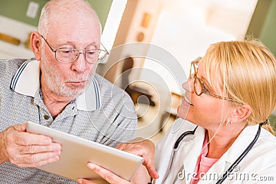 Female Doctor or Nurse Showing Senior Man Touch Pad Computer At Home Stock Photo