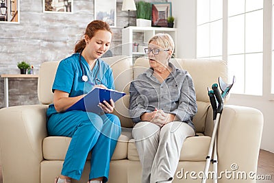 Female doctor in nursing home doing survey on senior woman Stock Photo