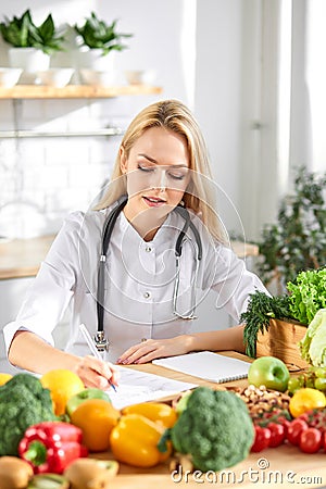 Female doctor nutritionist writing case history in officem dietitian prescribing recipe Stock Photo