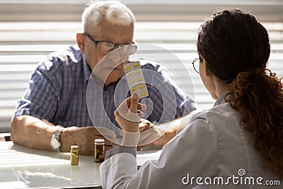 Female doctor pharmacist recommend effective pills to senior man oap Stock Photo