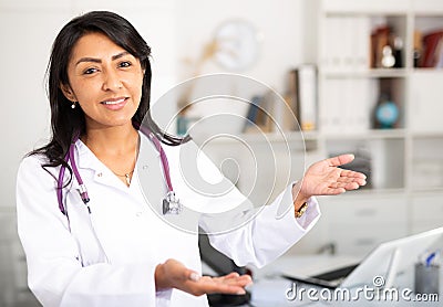 Female doctor politely inviting patient to medical office Stock Photo