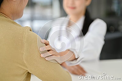 A female doctor`s hand on her patient`s shoulder to make her patient feel relaxed and reassured Stock Photo