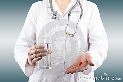 Female doctor's hand holding glass of water, giving pills. Close Stock Photo