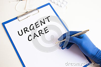 Female doctor's hand in a medical glove makes an inscription URGENT CARE in a document Stock Photo