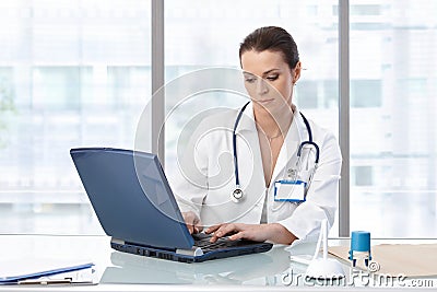 Female doctor sitting at table with laptop Stock Photo