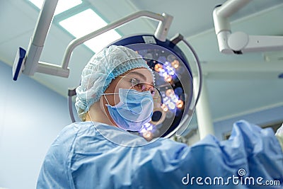 Female Doctor in Surgery Operating Hospital Room. Surgeon medic in protective work wear gloves, mask and cap Stock Photo