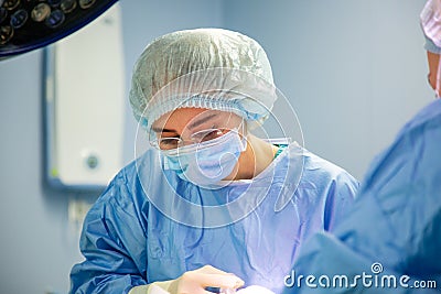 Female Doctor in Surgery Operating Hospital Room. Surgeon medic in protective work wear gloves, mask and cap Stock Photo