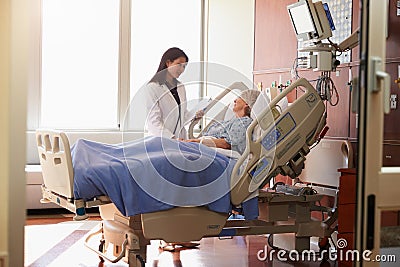 Female Doctor Talks To Senior Female Patient In Hospital Bed Stock Photo