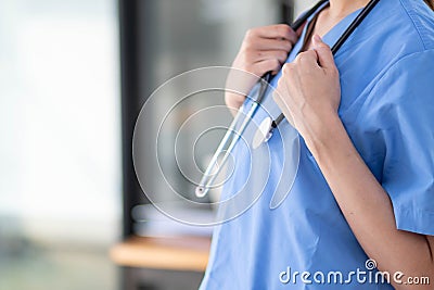 Female doctor in uniform holding a stethoscope waiting to examine a patient. A female doctor holds a stethoscope to prepare for Stock Photo