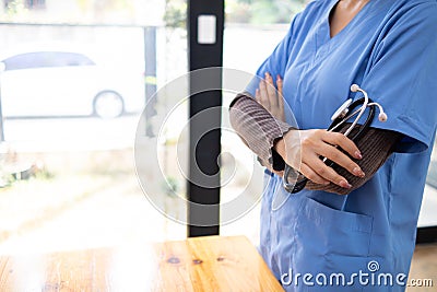 Female doctor in uniform holding a stethoscope waiting to examine a patient. A female doctor holds a stethoscope to prepare for Stock Photo