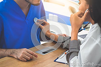 A Female doctor uses a stethoscope on a male patient to assess the heart and lung. Stock Photo