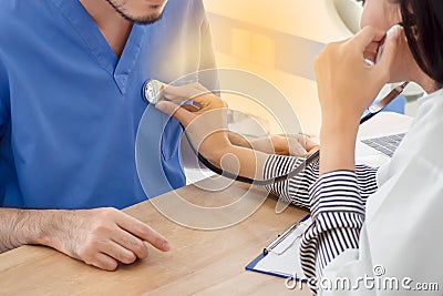 A Female doctor uses a stethoscope on a male patient Stock Photo