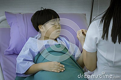 Female doctor who sits on sick child`s bed. Use hand to hold hands. Encourage patient influenz to sleep in hospital Stock Photo