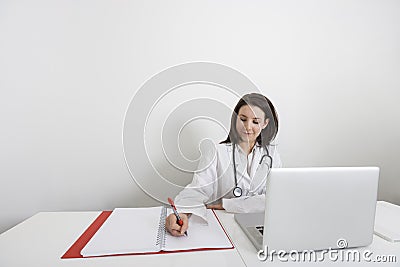 Female doctor writing on binder at desk in clinic Stock Photo