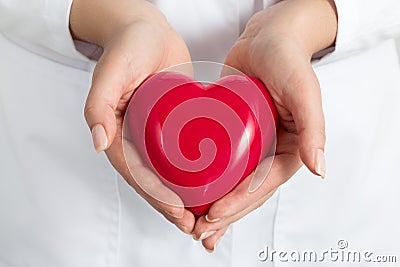Female doctors's hands holding and covering red heart Stock Photo