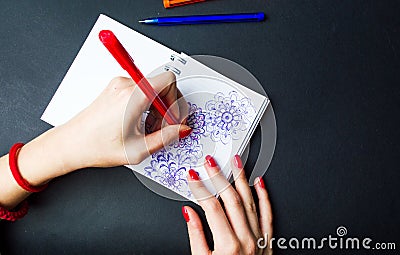 Female drawing flower shapes in notebook Stock Photo