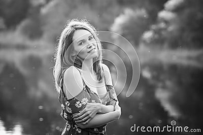 Female in dress bare shoulders on banks of pond Stock Photo