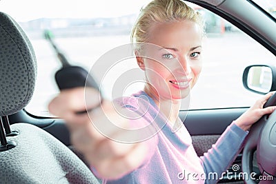 Female driver showing car keys. Young female driving happy about her new car or drivers license. Stock Photo