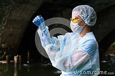 Female ecologist or biochemist examines a test tube with water from a city river in a collector Stock Photo