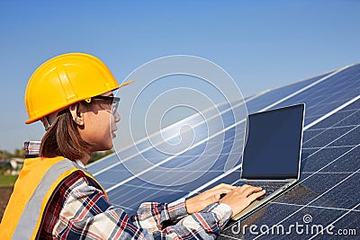 A female electrical engineer is using a laptop to control the operation of the solar panel Stock Photo
