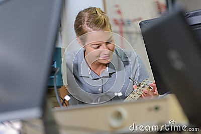 female electronics worker viewed between two computor monitors Stock Photo