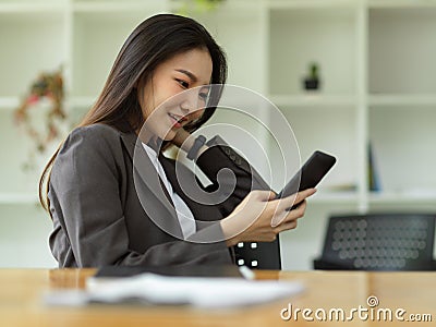 Female employee relaxed on her smartphone, scrolling through social media Stock Photo