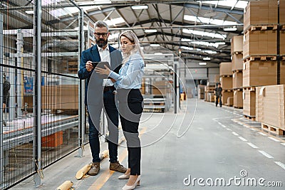 Female engineer and male production manager standing in modern industrial factory, talking about production Stock Photo