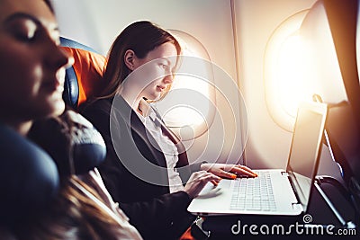 Female entrepreneur working on laptop sitting near window in an airplane Stock Photo