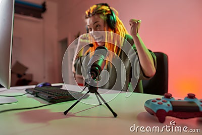 Female esport gamer, woman in headphones looking emotional, playing online video game on PC while recording, filming Stock Photo