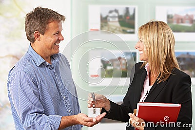 Female Estate Handing Over Keys Of New Home Stock Photo