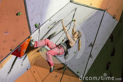 Female extreme climber hanging on arm and feet Stock Photo