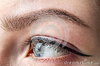 Female eye of blue color of a young girl close-up. Eye and eyebrow makeup.Permanent makeup for eyelids and eyebrows Stock Photo