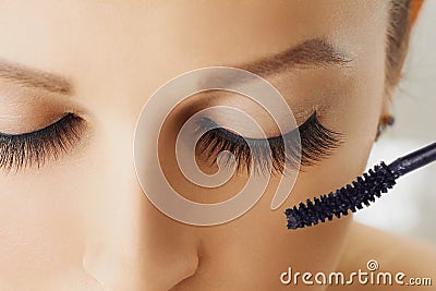 Female eye with extreme long eyelashes and brush of mascara. Make-up, cosmetics, beauty Stock Photo