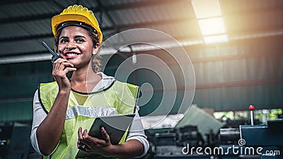 Female factory worker using handheld radio receiver for communication. Stock Photo