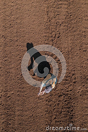 Female farmer examining ploughed field soil, drone photography top view Stock Photo