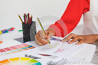 Female fashion designer drawing a sketch at desk in design studio Stock Photo