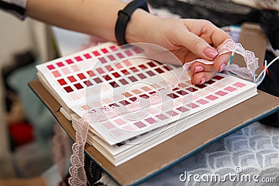 Female fashion designer holding color samples choosing fabric textile at workplace Editorial Stock Photo